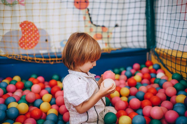 featured-image Child Boy Playing with Plastic Colorful Play Balls in Ball Pit