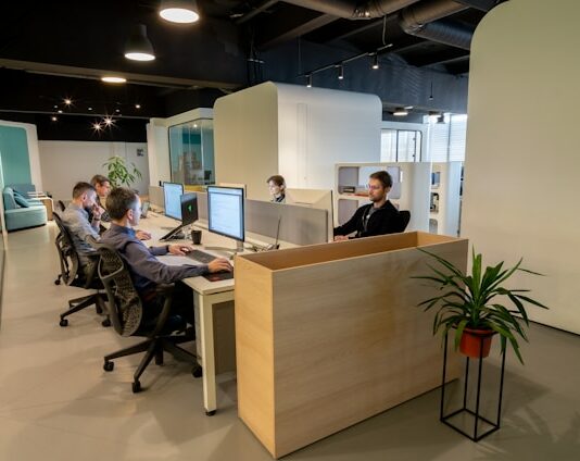 a group of people sitting at desks in an office