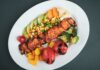grilled meat with sliced lemon and sliced tomatoes on white ceramic plate