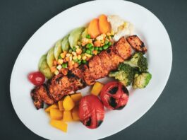 grilled meat with sliced lemon and sliced tomatoes on white ceramic plate